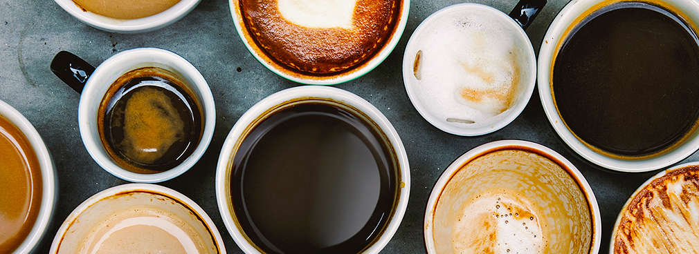 Mehrere Tassen unterschiedlicher Kaffeespezialitäten stehen nebeneinander auf einem Tisch