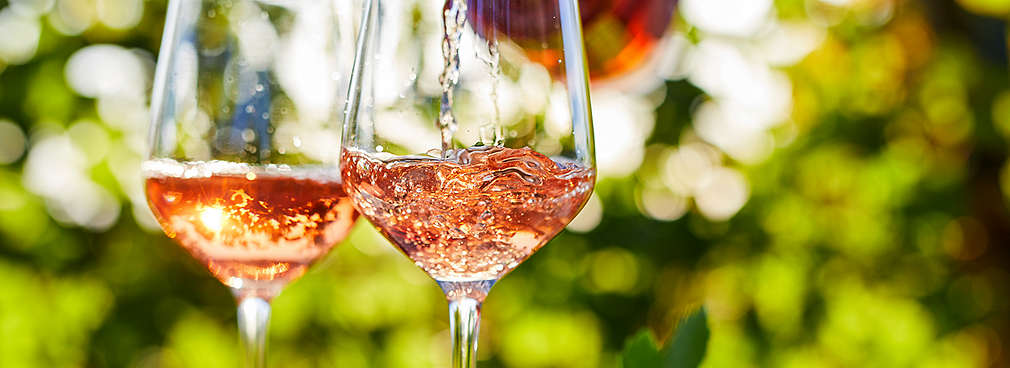 Zwei Gläser mit Roséwein, Hintergrund mit Gartenatmosphäre