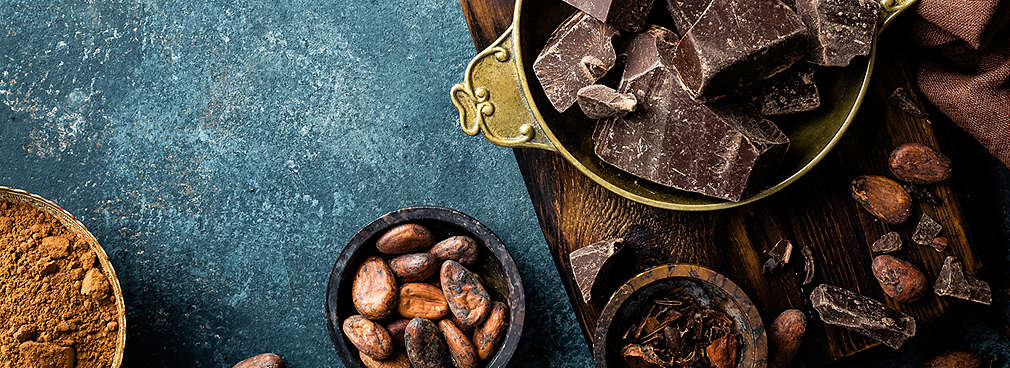 Schokolade und Kakaobohnen, angerichtet in unterschiedlichen Schälchen 
