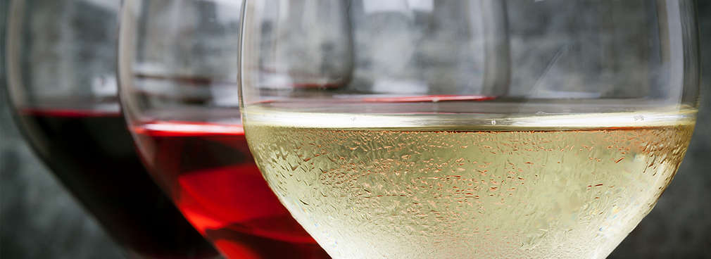 Mehrere Gläser Wein hintereinander gefüllt mit Weißwein, Roséwein und Rotwein