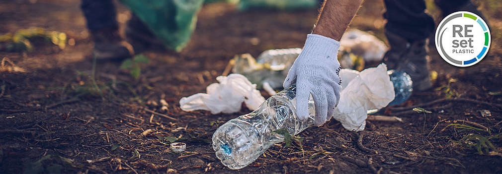 Menschen sammeln Verpackungsmüll aus Plastik auf, der achtlos in die Natur geworfen wurde