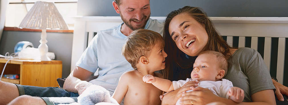 Eltern und Kinder sitzen gemeinsam auf einem Bett