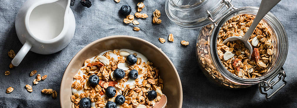 Eine Müslischale mit Blaubeeren und ein Kännchen laktosefreier Milch daneben