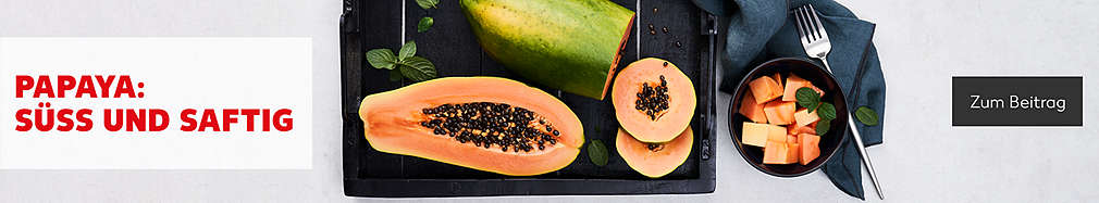 Papaya – süß und saftig; aufgeschnittene Papaya auf einem Brett, daneben Papayastückchen in Schüssel sowie Gabel und Serviette