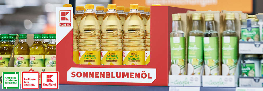 Regal mit einem Karton voller K-Classic Sonnenblumenöl-Flaschen, die das „Bewusster verpackt“-Logo tragen