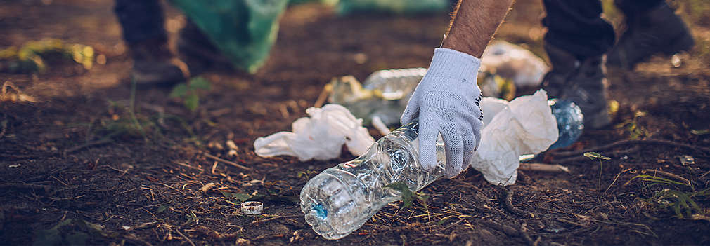 Menschen sammeln Verpackungsmüll aus Plastik auf, der achtlos in die Natur geworfen wurde