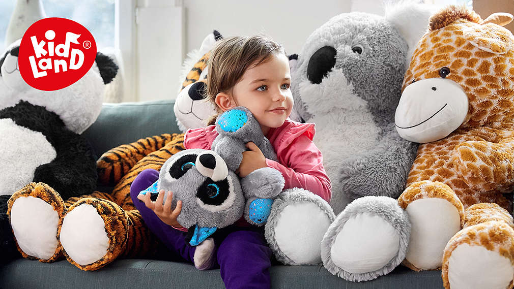Child sits between many cuddly toys. Kidland® logo