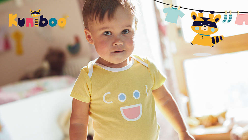 Toddler in a child's room. Kuniboo® logo and graphic of the raccoon Kuniboo.