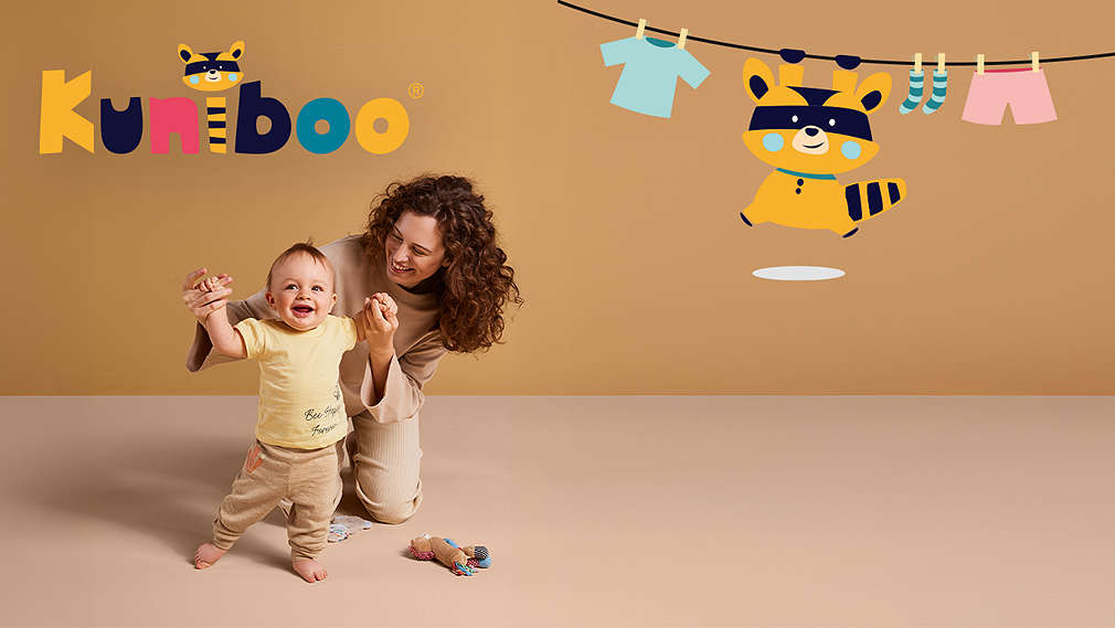 Toddler in Kuniboo clothes with his mom. Kuniboo logo on the bottom right.