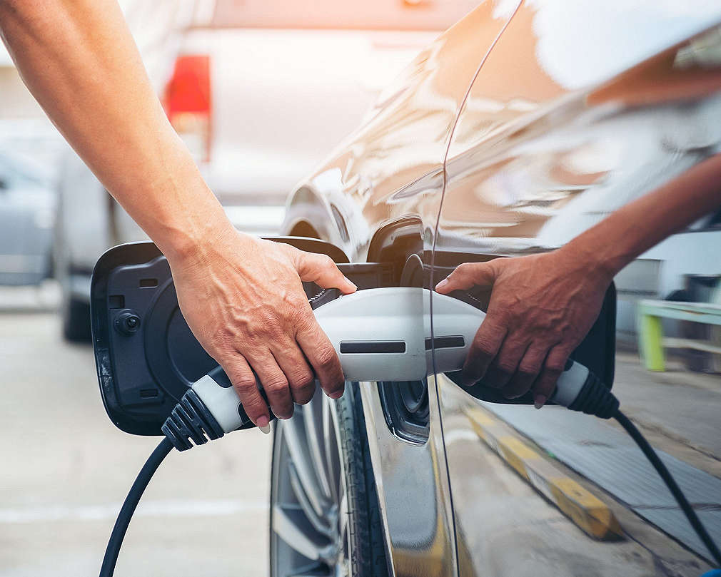 Człowiek ładuje samochód elektryczny