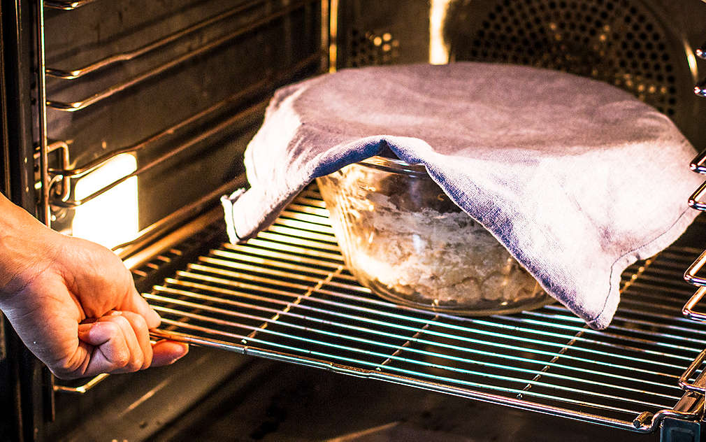 Na ruszcie piekarnika stoi przykryta miska z ciastem drożdżowym.