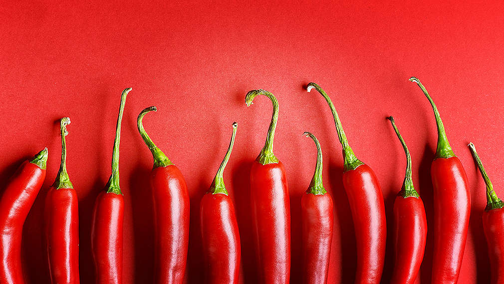 On a red background, you can see a line of red chilis.