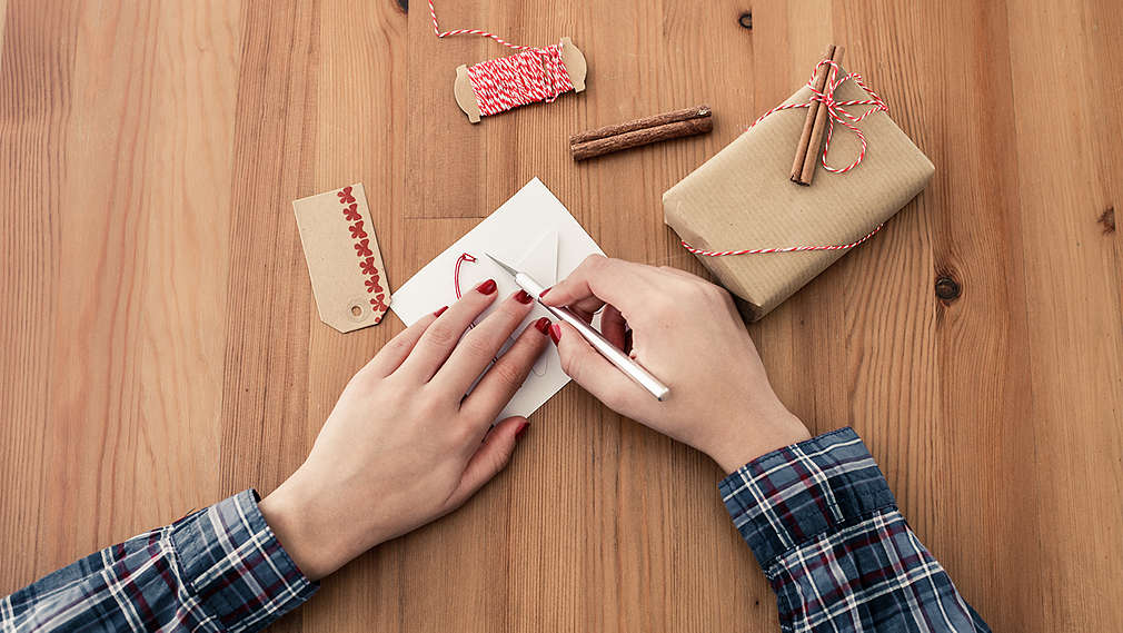 Záber ako ruky na stole vyrábajú originálne vianočné prianie.