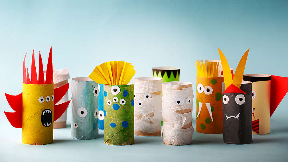 On a blue-grey background, you can see a group of hand -crafted monsters made out of toilet paper rolls with colourful faces and hair cuts.