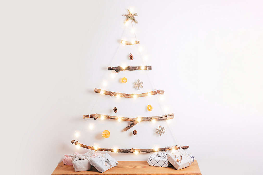 Minimalistyczna osdoba w kształcie płaskiej białej choinki ze złotymi wstążkami