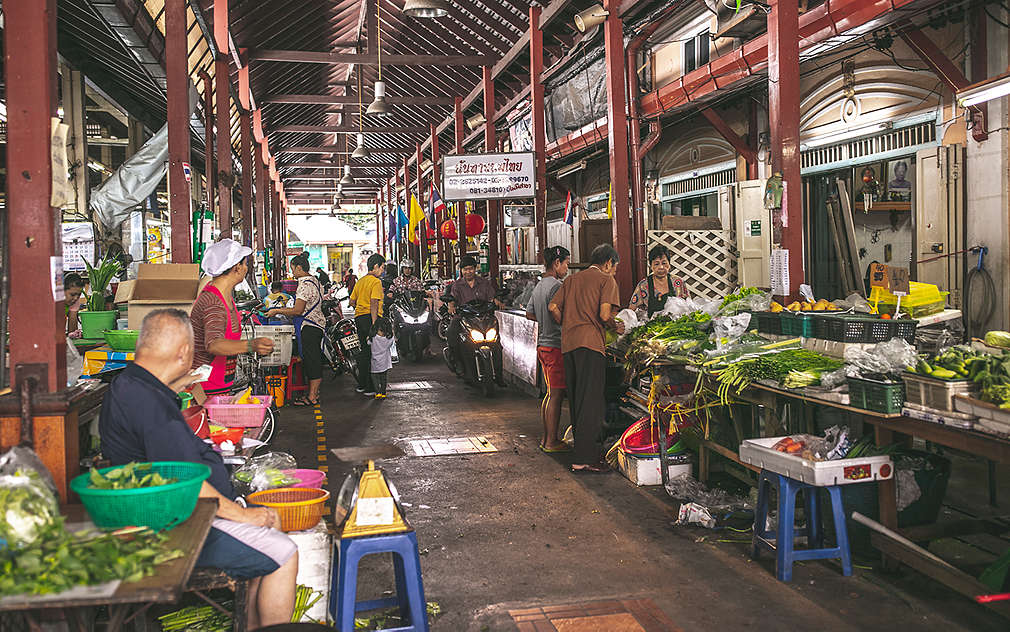 Dvě řady stánků s čerstvým ovocem a zeleninou na zastřešeném trhu Nang Loeng v Bangkoku.