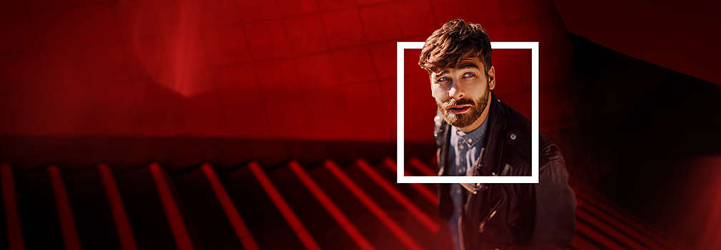 Mężczyzna wyciąga głowę z prostokątu namalowanego białą farbą na bordowym tle