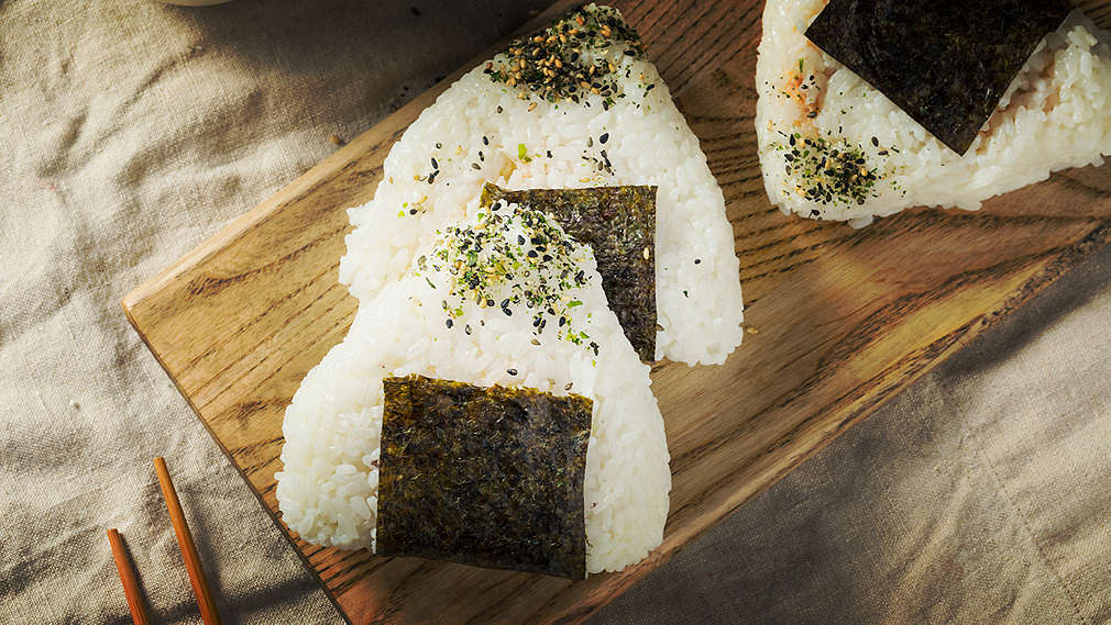 Se pot vedea onigiri pe un tocător din lemn.