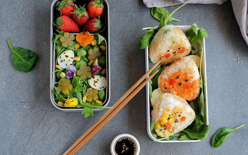 Onigiri v krabičce na svačinu se salátem jako přílohou.