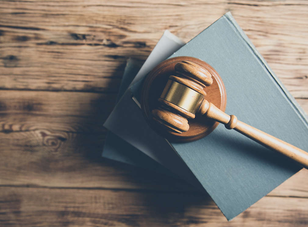 A gavel for the court lies on several books, symbolizing laws.