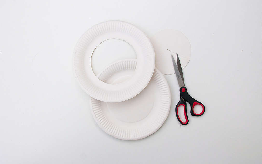 Două farfurii de carton cu un cerc decupat, astfel încât să arate ca niște inele, lângă ele se află o foarfecă.