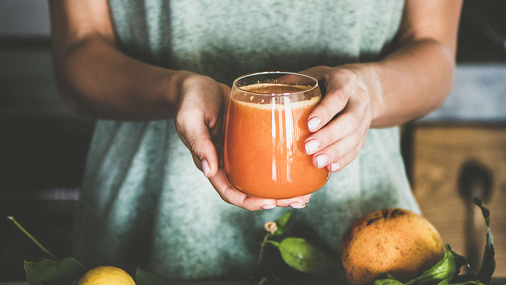 Žena drží v ruce sklenici s ovocnou šťávou.