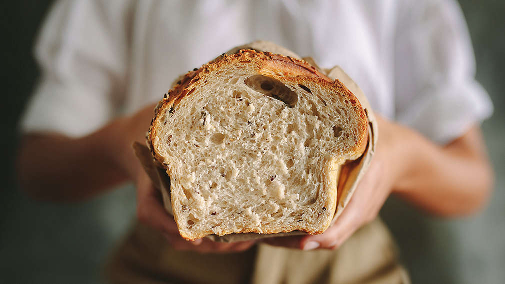 Někdo drží bochník chleba.