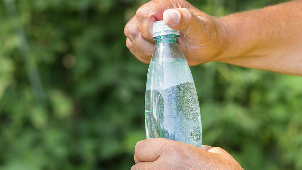 Někdo otevírá láhev vody