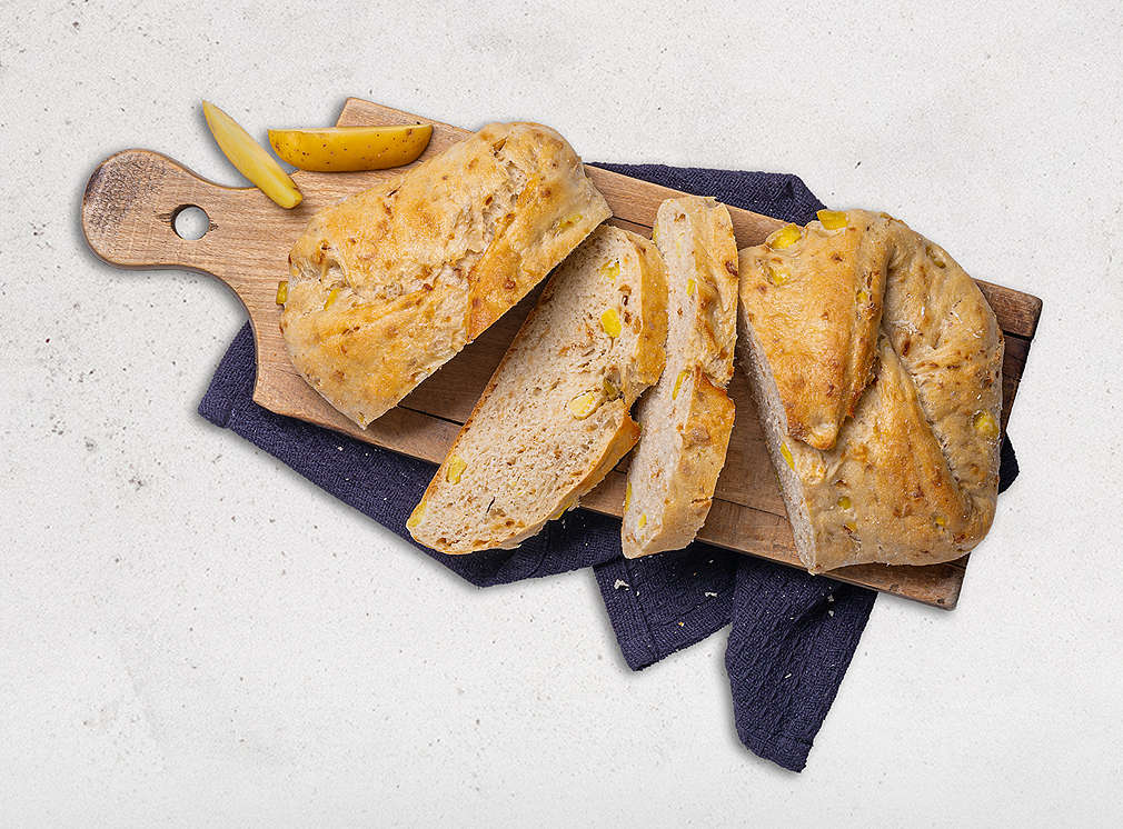 Zwiebelbrot auf einem Holzbrett und schwarzem Handtuch aufgeschnitten