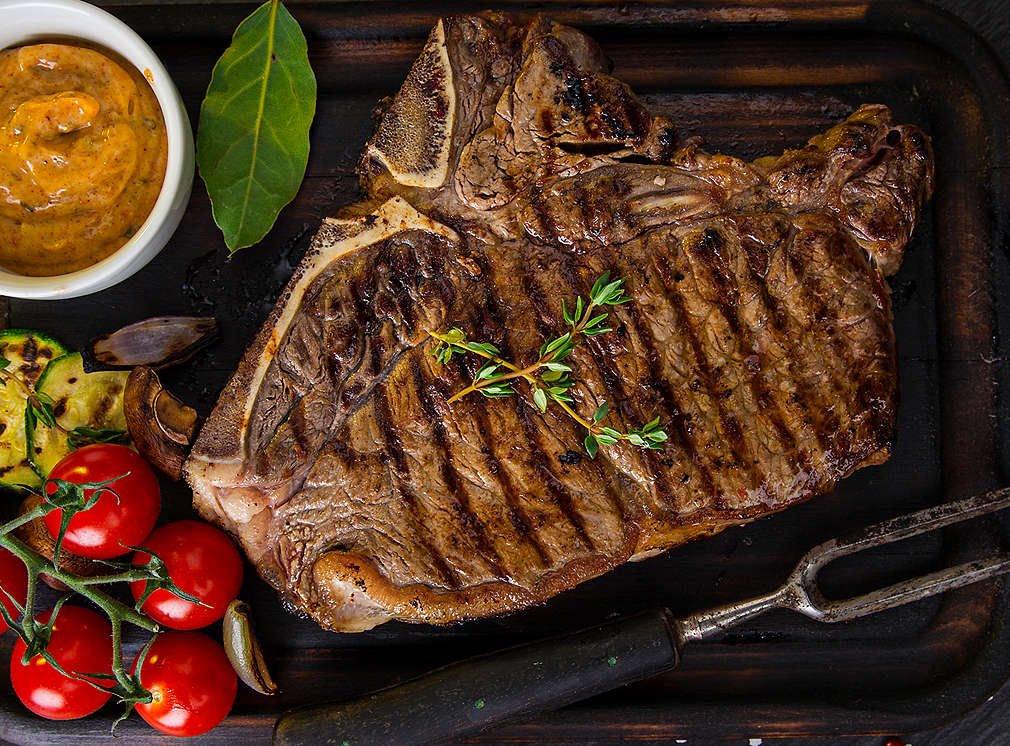 Gegrilltes Steak, daneben Tomaten und Soße