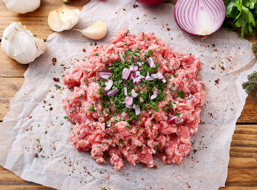 Hackfleisch auf Papier mit Kräutern und Zwiebeln