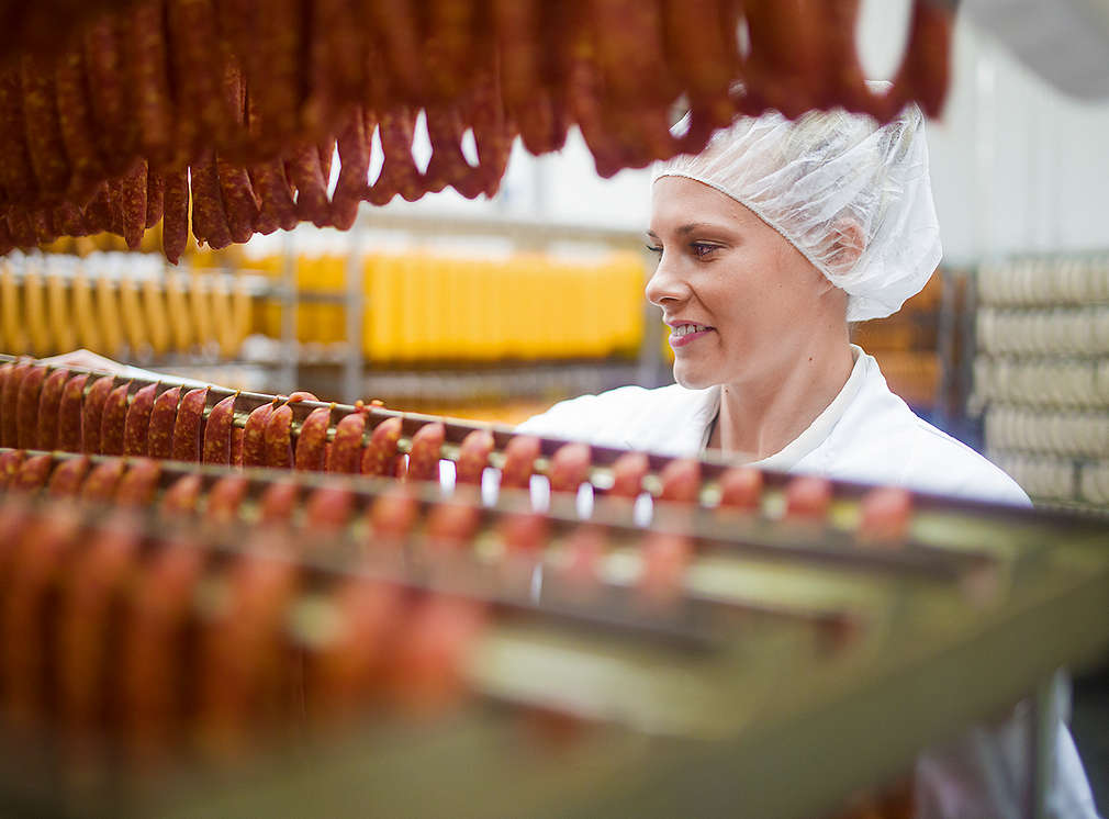 Metzger im Fleischwerk hält Kiste mit frischen Fleischprodukten