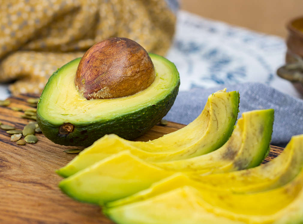 Avocadohälfte, daneben geschnittene Spalten