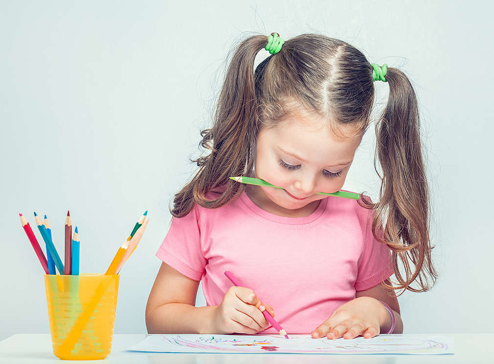 Mädchen mit Stift im Mund zeichnet