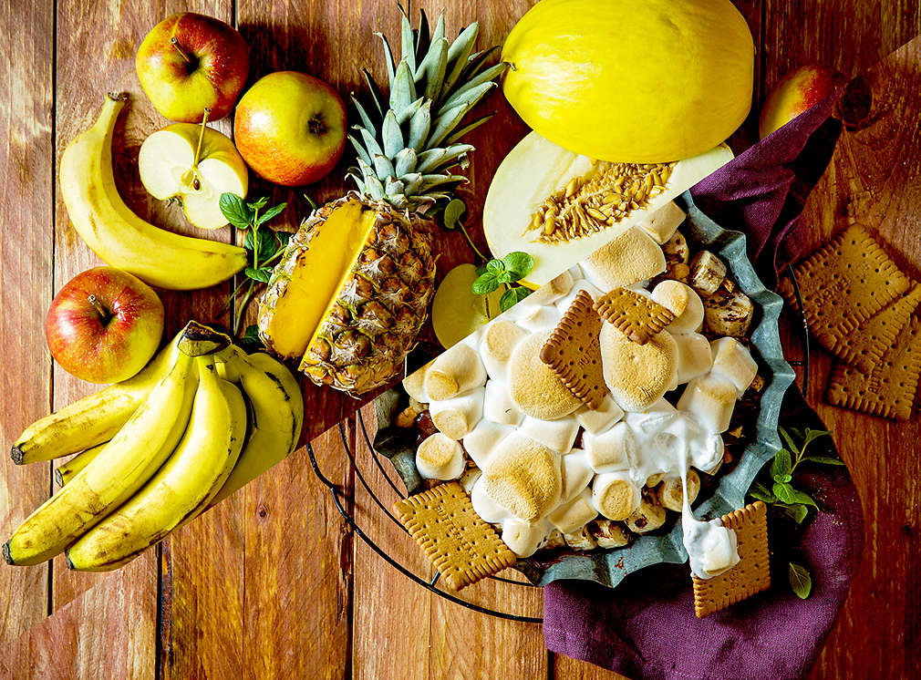 versch. Obst roh und gegrillt auf einem Holztisch