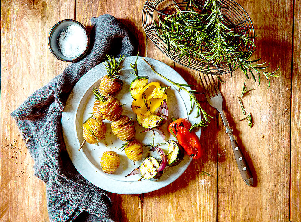 gegrillte Kartoffeln mit Rosmarin liegen auf einem Holztisch