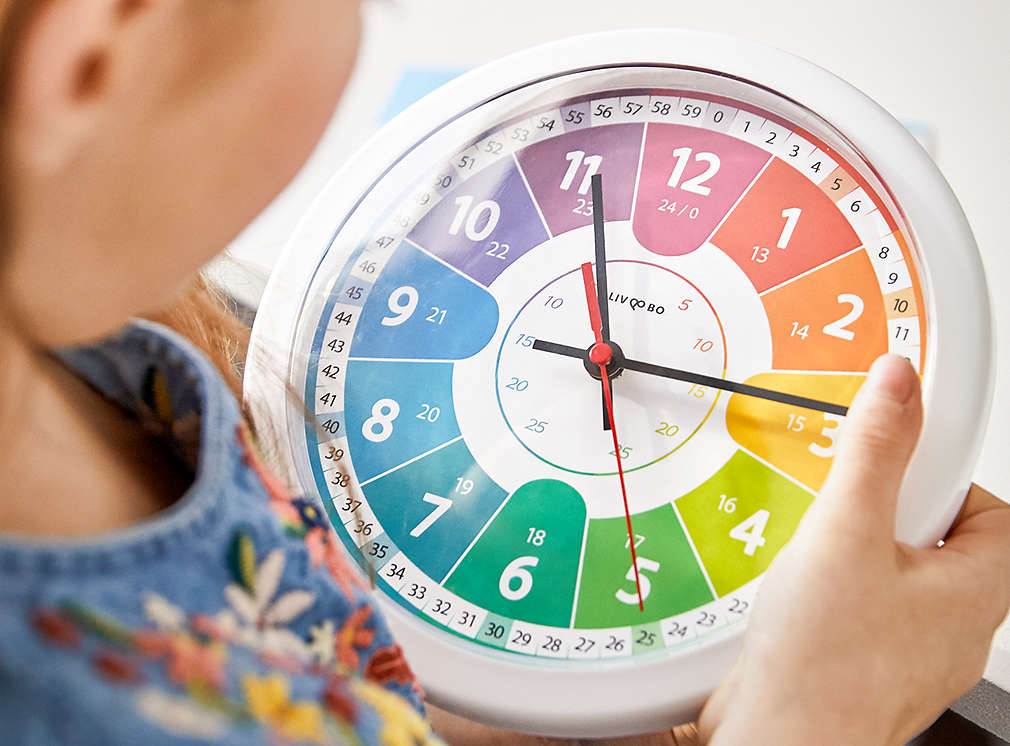 Dziecko z dużym kolorowym zegarem do nauki.