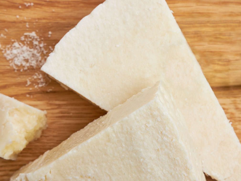 Imagine detaliată a unei bucăți de Pecorino proaspăt pe un tocător din lemn
