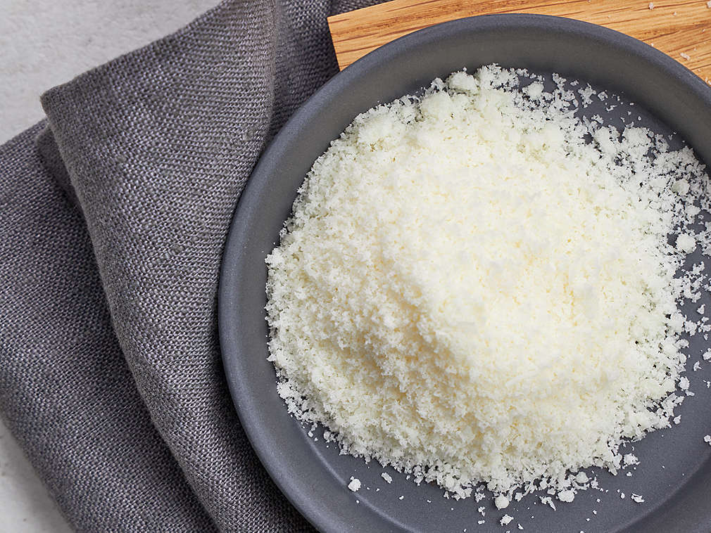 Imagine detaliată cu Pecorino proaspăt ras pe o farfurie gri închis, cu un prosop de bucătărie gri închis așezat sub aceasta