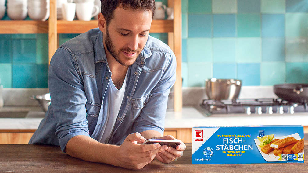 A man uses his mobile phone to check where his K-Classic fish sticks come from.