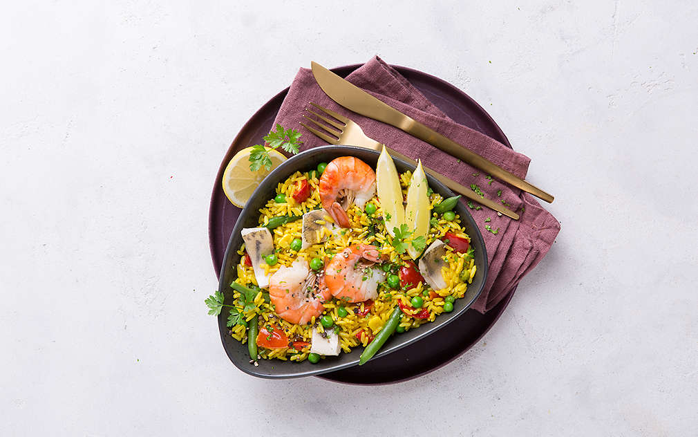 Prikazana je zdjela s kozicama, rižom i povrćem, među ostalim s graškom, grahom i paprikom.