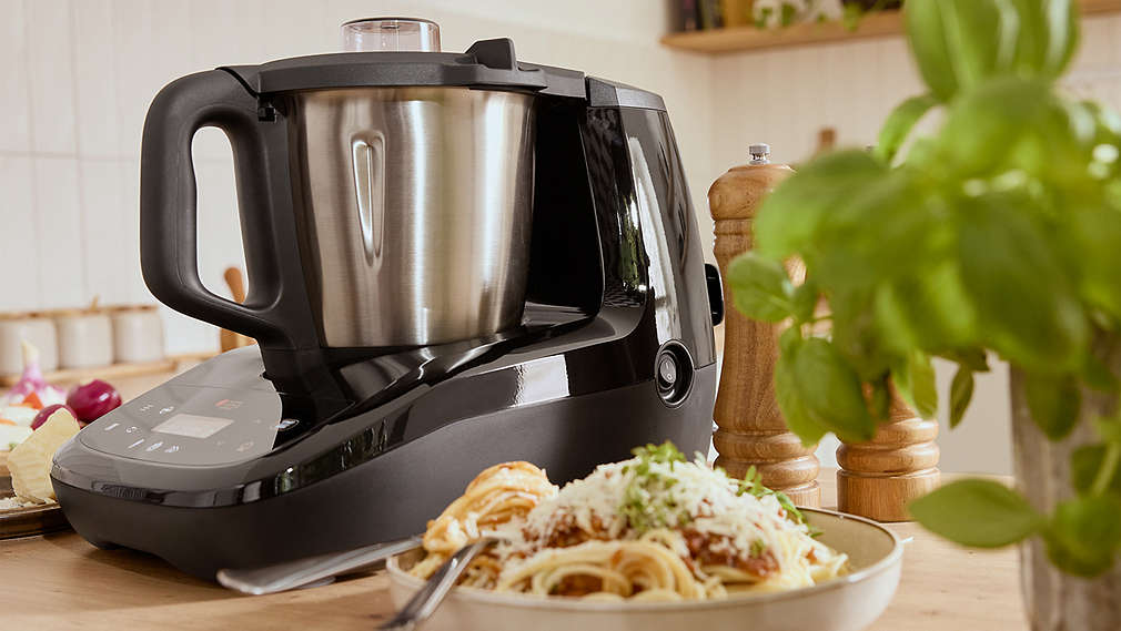 Eine schwarze SILVERCREST Monsieur Cuisine steht auf einer Küchenzeile hinter einem Teller mit frisch zubereiteter Pasta., Eine schwarze SILVERCREST Monsieur Cuisine steht auf einer K�chenzeile hinter einem Teller mit frisch zubereiteter Pasta.