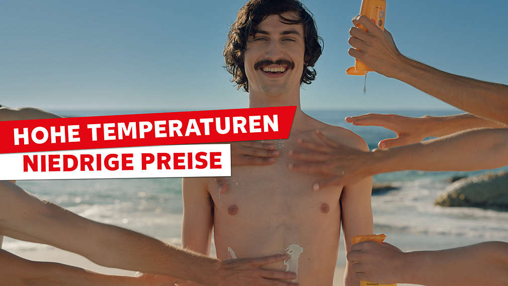 Mann steht am Strand und wird mit Sonnenschutz eingerieben; Schriftzug: Hohe Temperaturen niedrige Preise