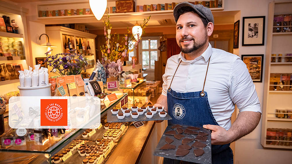 Abbildung: Ein Mann mit Gebäck in den Händen; Logo: Eat the World