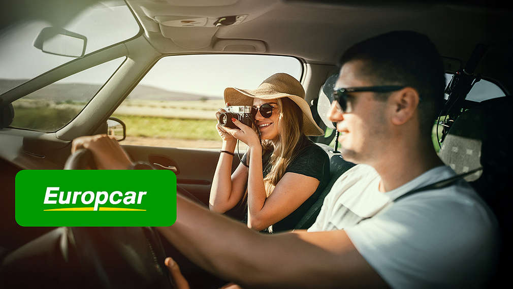 Abbildung: Zwei Menschen sitzen im Auto Logo: Europcar
