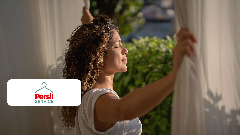 Abbildung: Eine Frau öffnet die Vorhänge; Logo: Persil Service