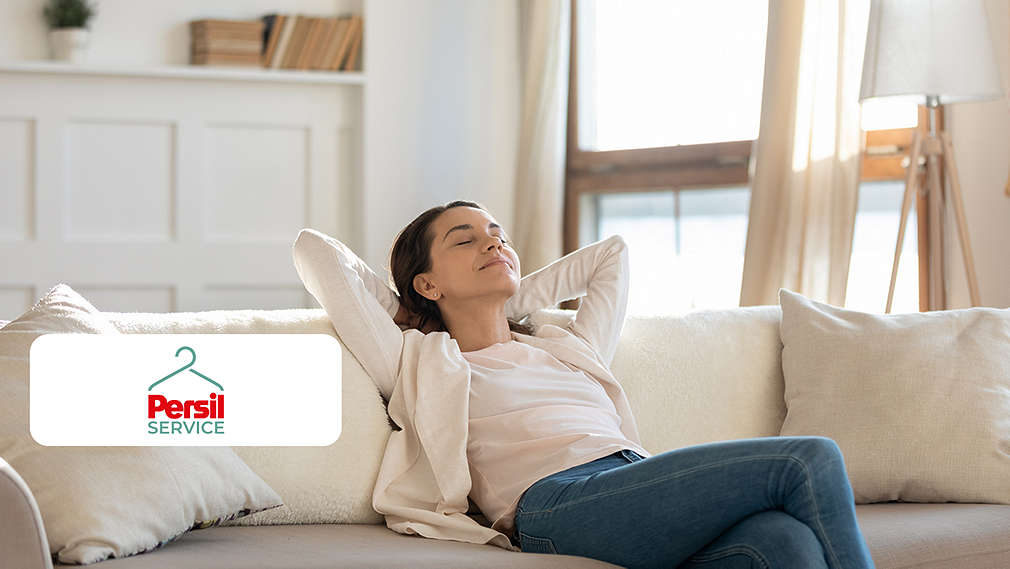 Abbildung: Frau sitzt entspannt auf einem Sofa; Logo: Persil Service