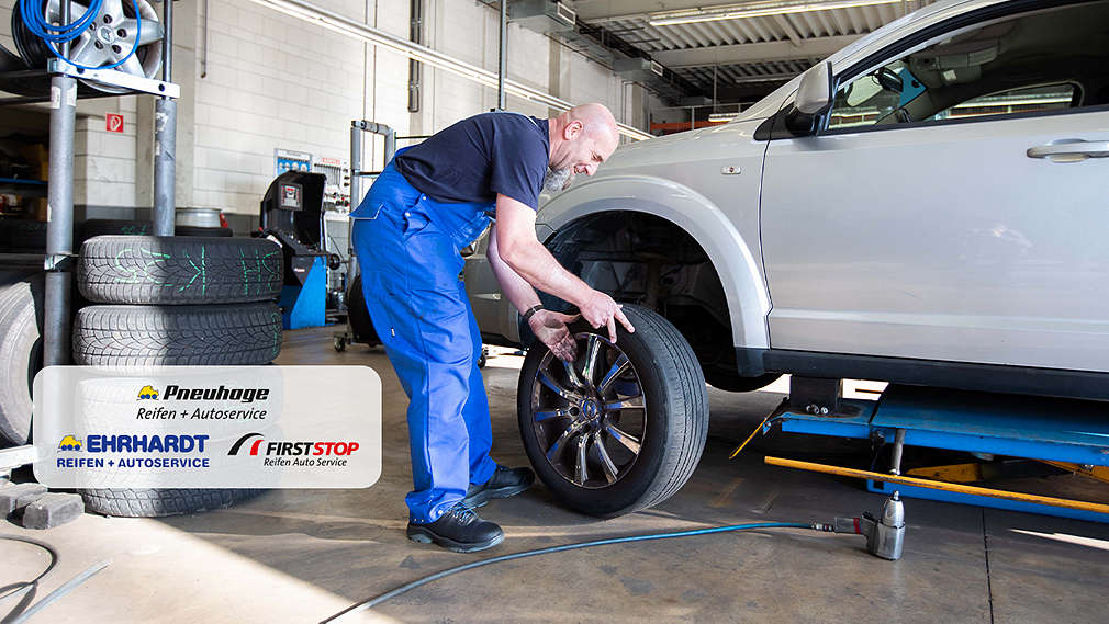 Abbildung: Ein Mann arbeitet in der Werkstatt an einem Auto; Logo: Pneuhage; Firststop; Ehrhardt