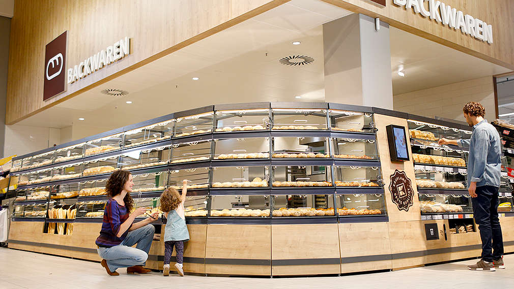 Bäckerei im Kaufland: Familie mit Kind wählt an der Bäckerei-Theke Backwaren aus.