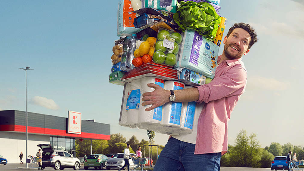 Изображение на млад мъж, носещ много продукти в ръце